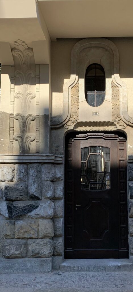 Restauriertes Jugendstil-Hausportal mit Sandsteinsockel und Stuckornament