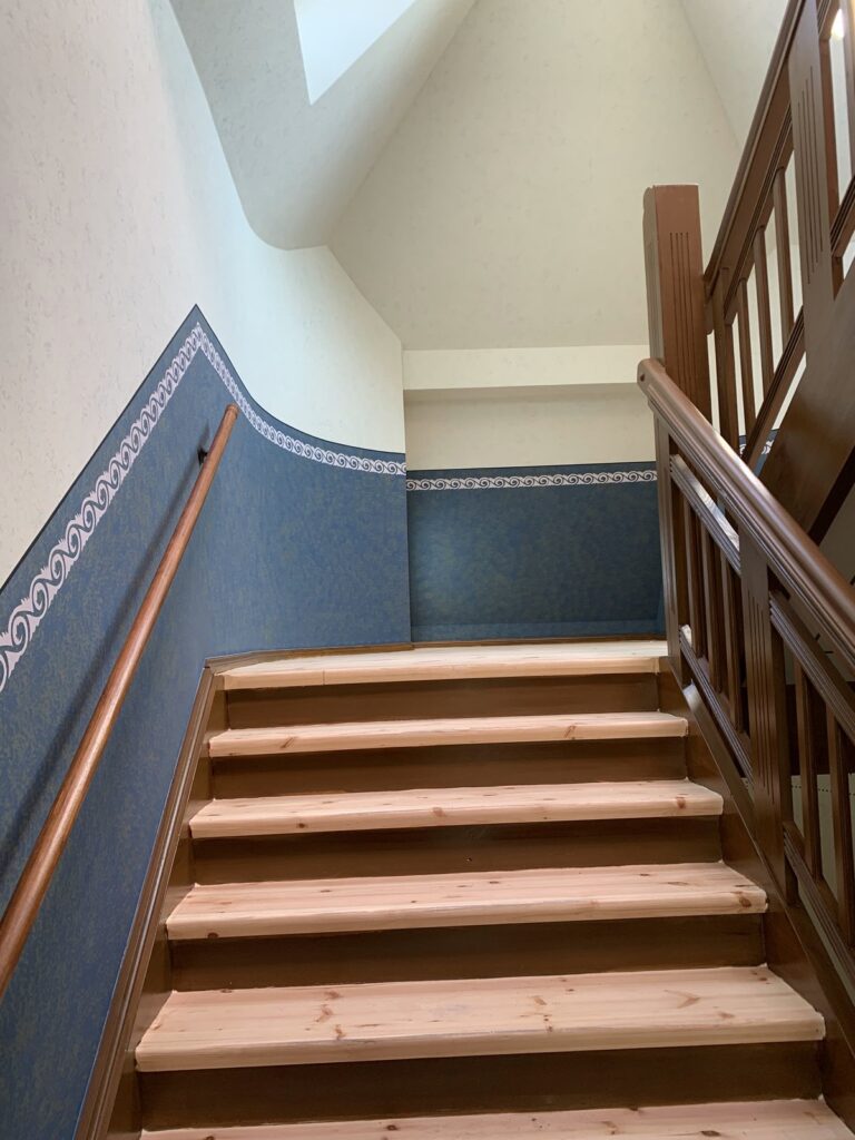 Saniertes Treppenhaus in historischer Farbfassung mit Schablonenfries